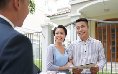 Cheerful young Vietnamese family talking to real estate agent in front of house